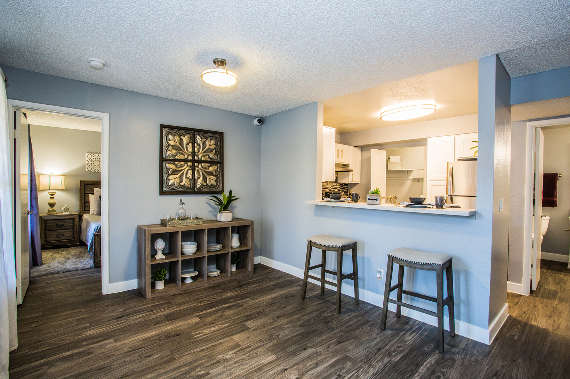 Modern apartment interior with open kitchen, stylish barstools, and elegant decor.
