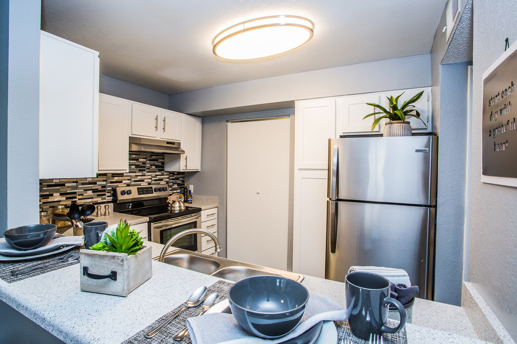 Modern kitchen with stainless steel appliances, stylish countertops, and decorative backsplash.