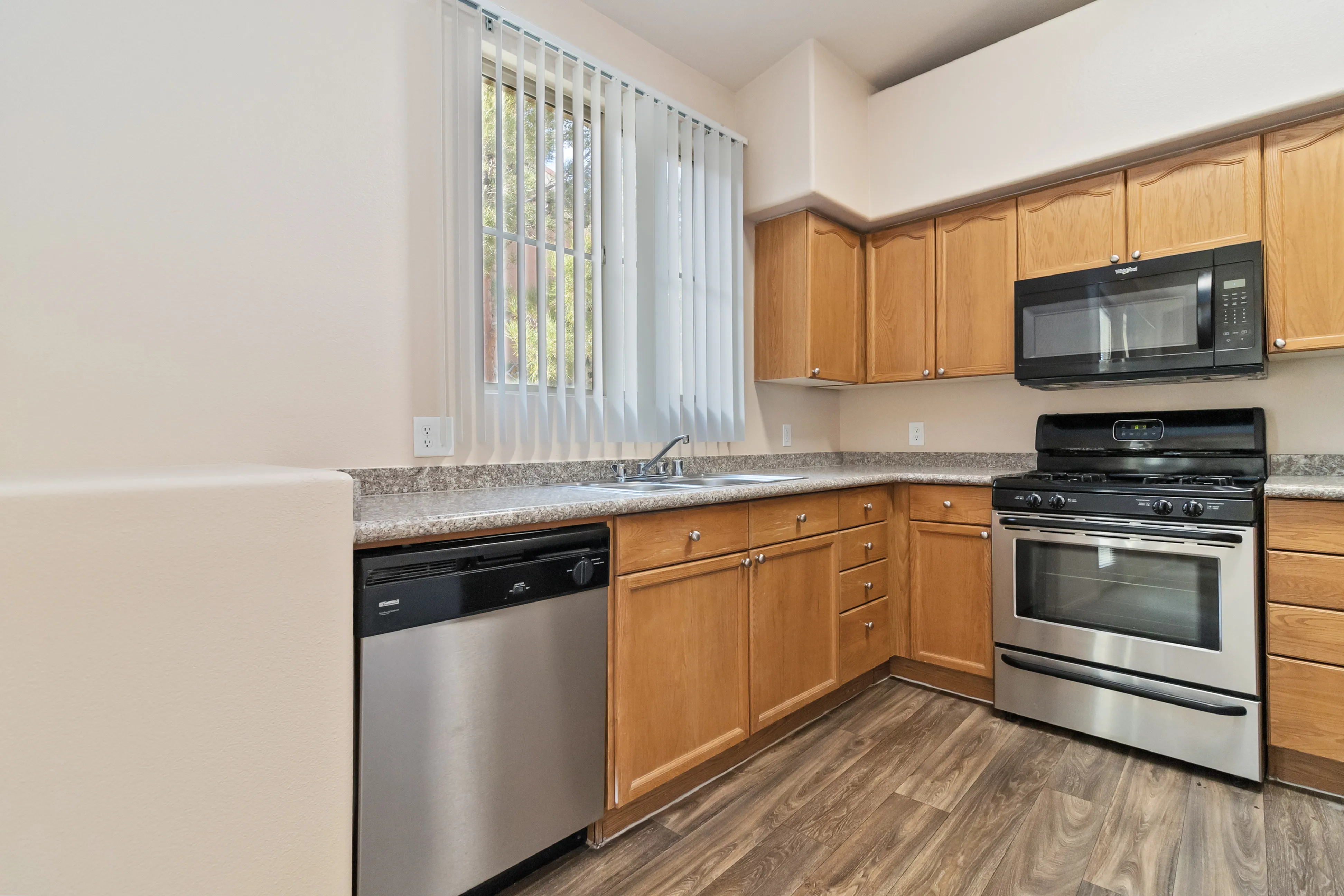 Modern kitchen with stainless steel appliances, wooden cabinets, and large window for natural light.