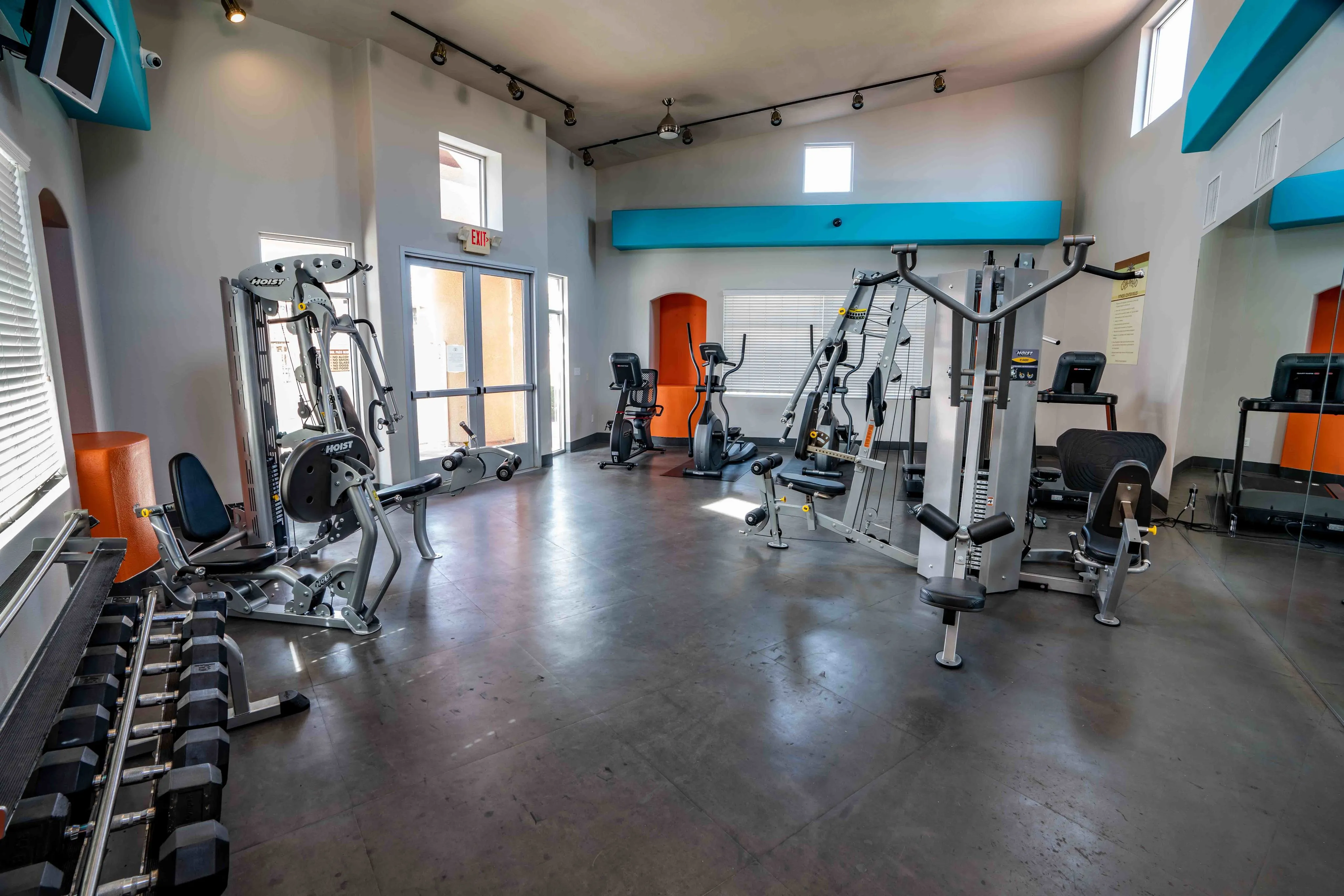 Modern gym facility with various exercise machines and free weights in a bright, spacious room.