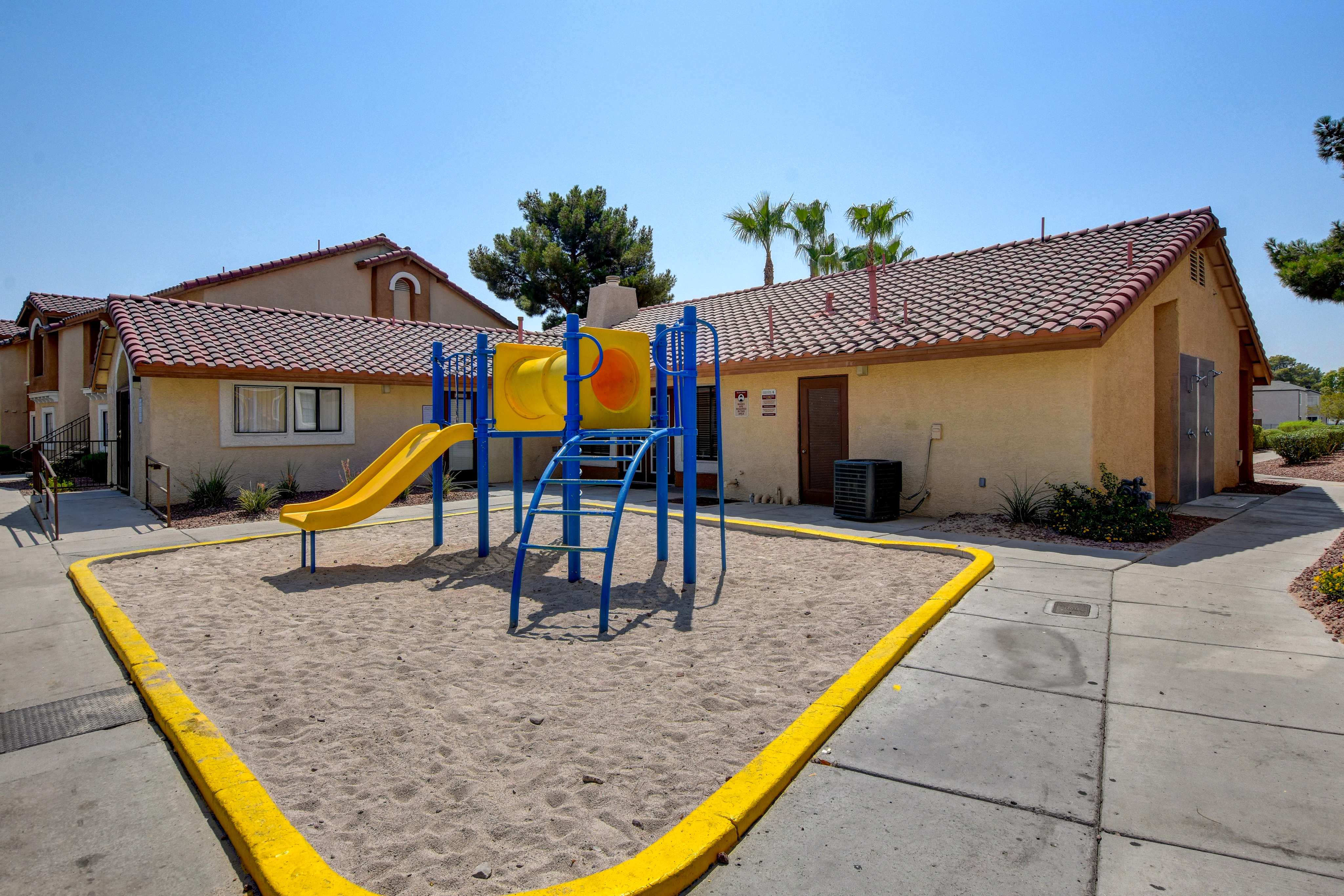 Inviting playground with colorful slides and climbing structure beside a charming apartment building.