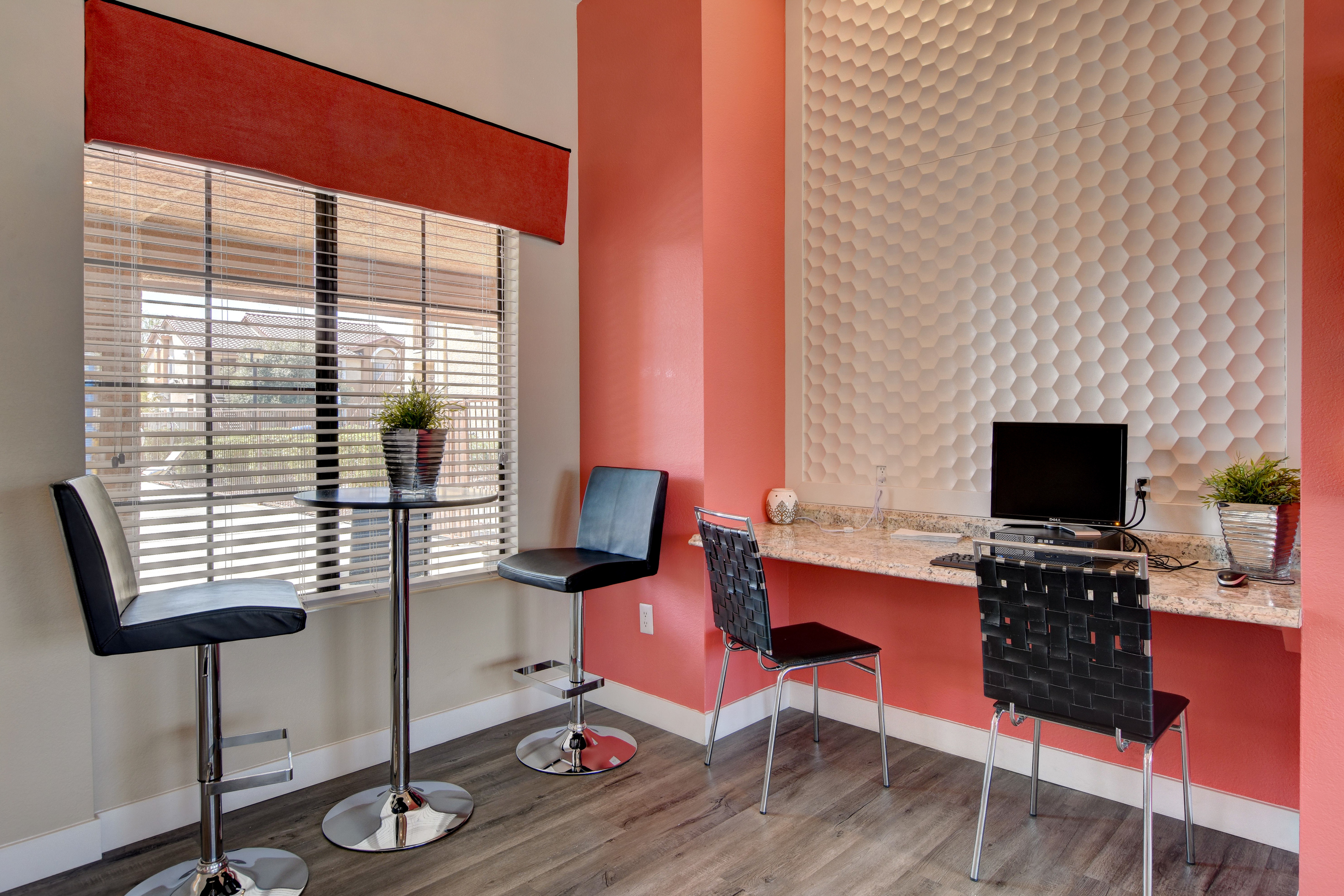 Chic home office nook with modern decor and ample natural light, featuring a stylish bar table and computer desk.
