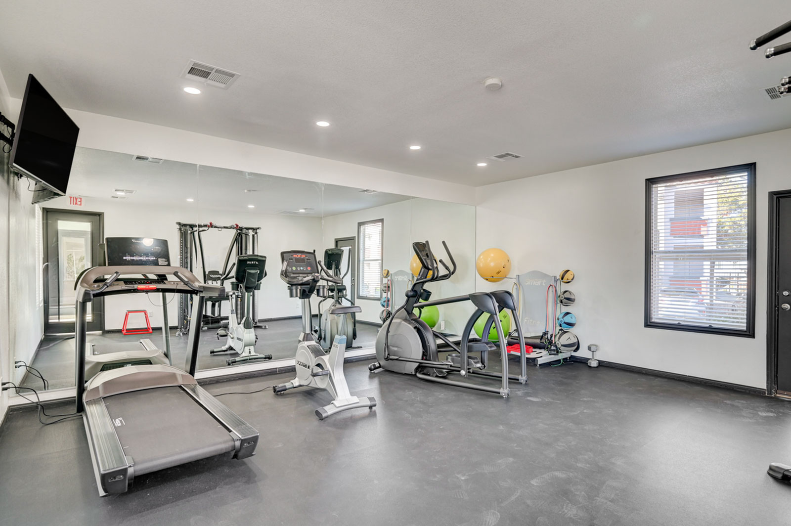 Modern fitness center with state-of-the-art treadmills, exercise bikes, and weight machines in a sleek, mirror-walled room.
