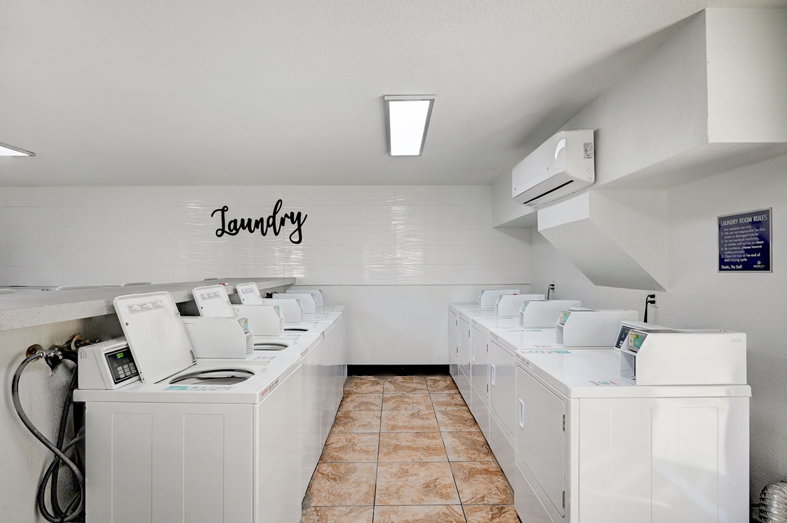 Bright and modern laundry room equipped with state-of-the-art washing machines, perfect for convenient apartment living.