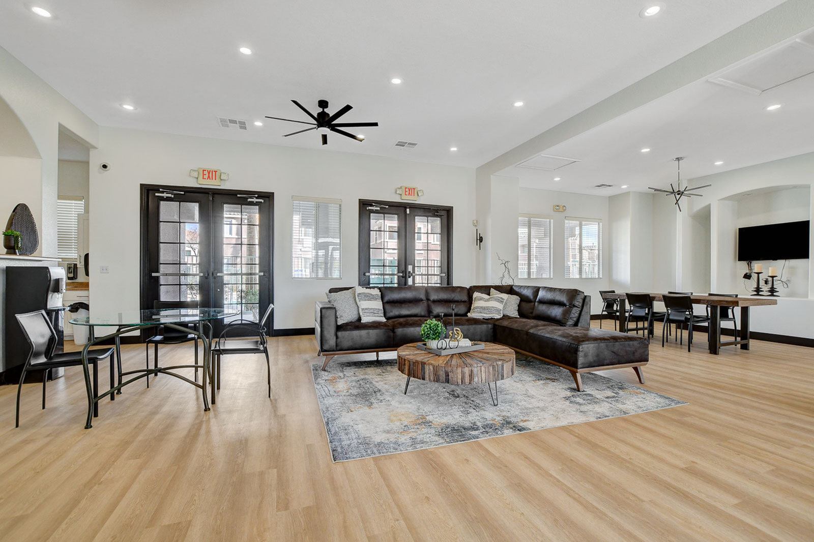 Luxurious open-concept living area with a stylish leather sectional, modern dining table, and warm wooden flooring, perfect for entertaining.