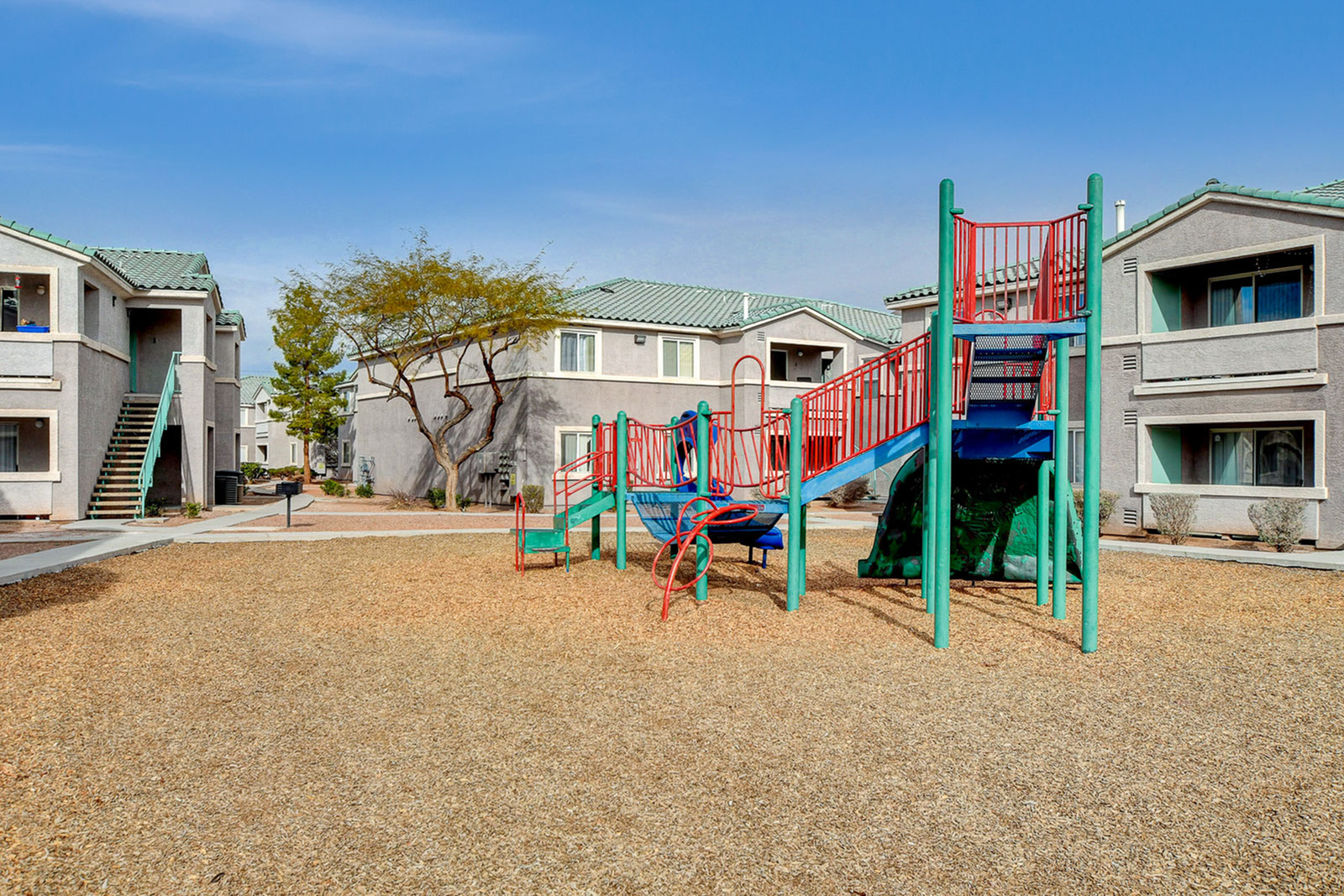 Charming apartment complex with modern buildings and a colorful playground, perfect for families seeking a vibrant community.