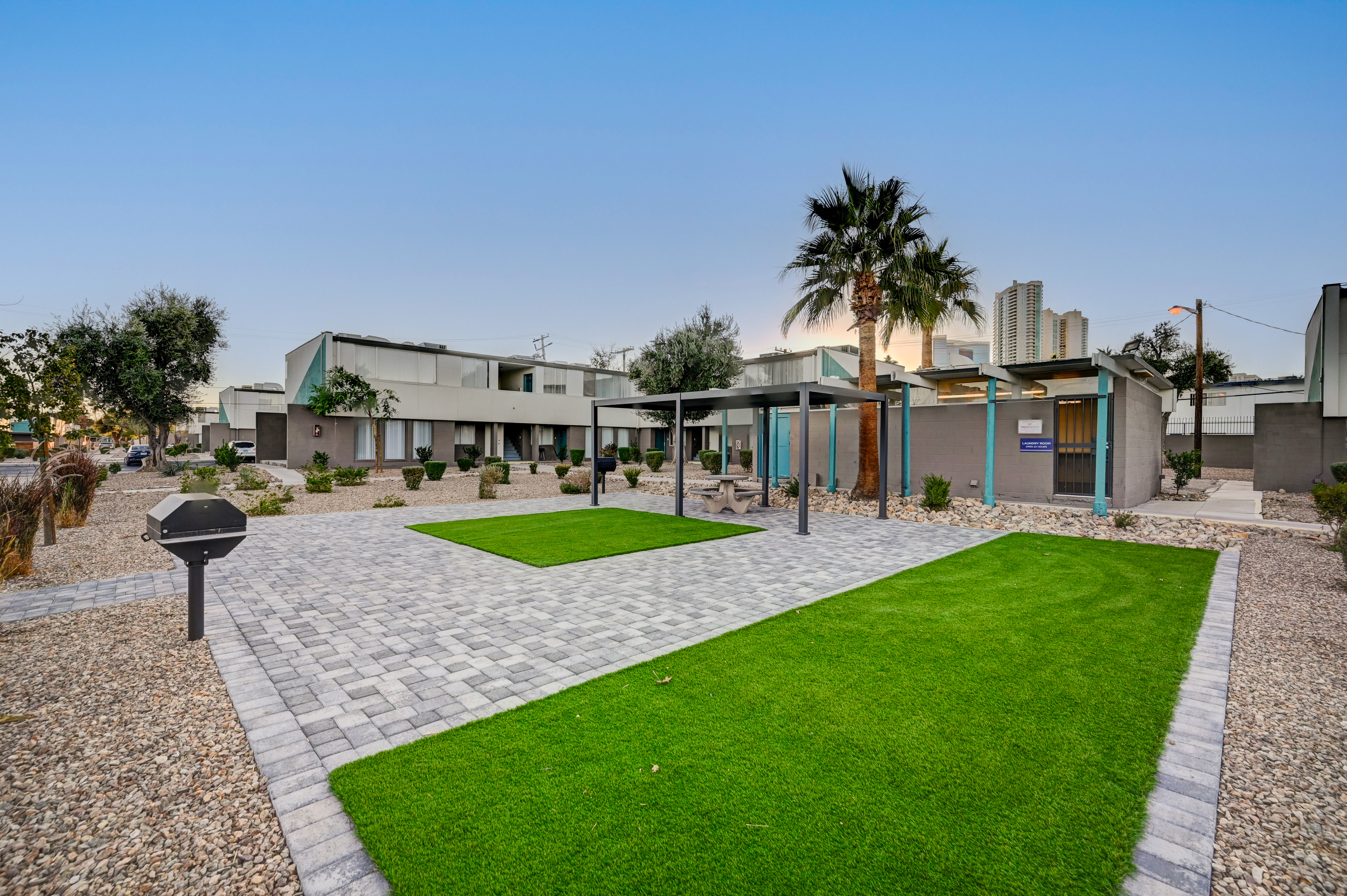 Modern apartment exterior with lush green lawn, elegant stone walkway, and inviting outdoor seating under a stylish pergola.