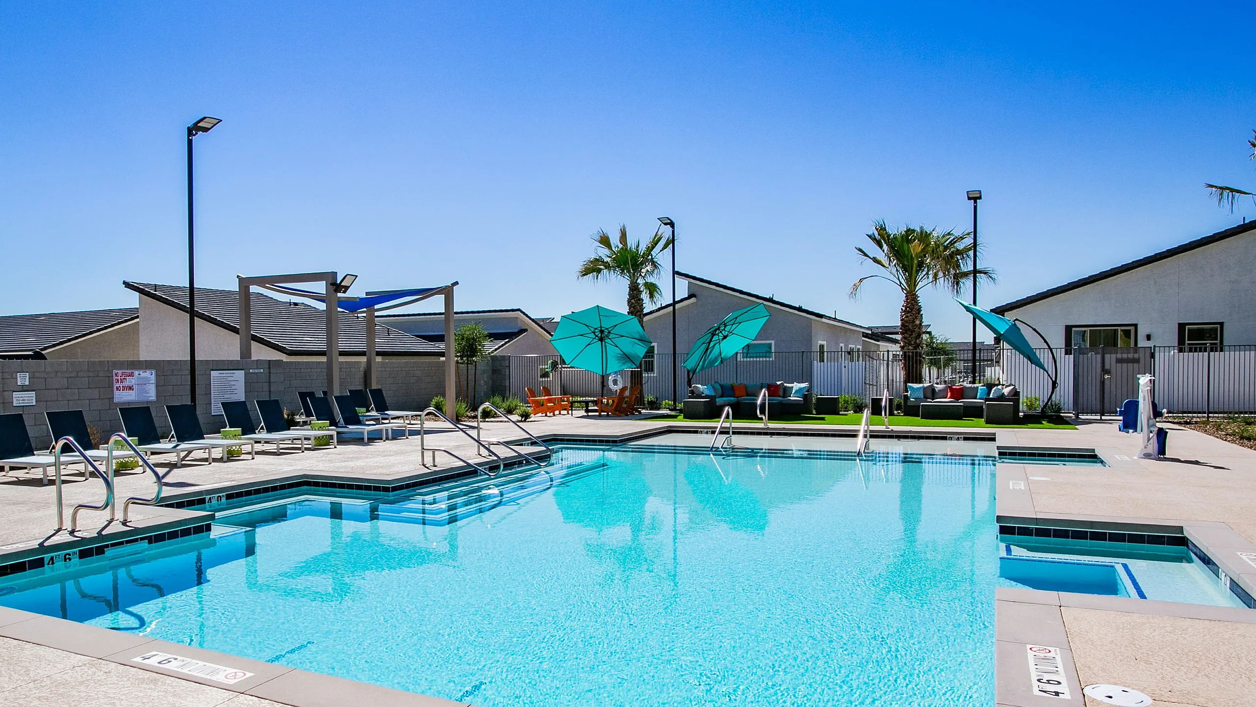 Chic outdoor poolside scene with turquoise lounge chairs and shaded umbrellas in a sunny setting.