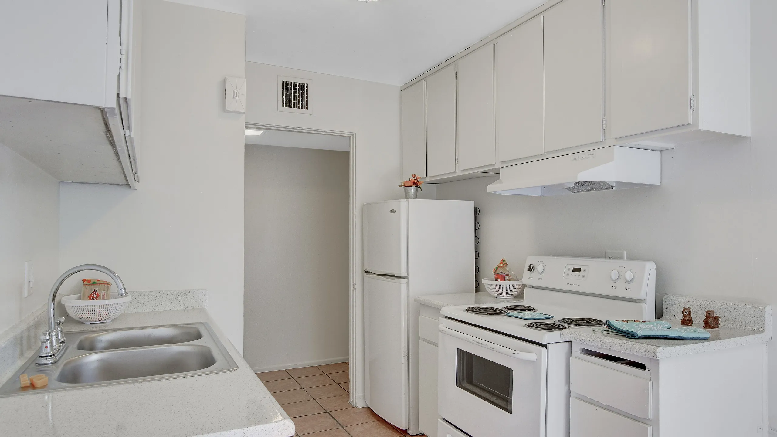 Bright kitchen with white cabinetry, modern appliances, and a double sink.