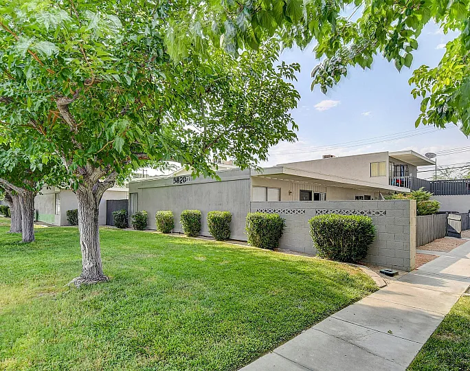 Inviting suburban home with lush green lawn and tree-lined pathway.
