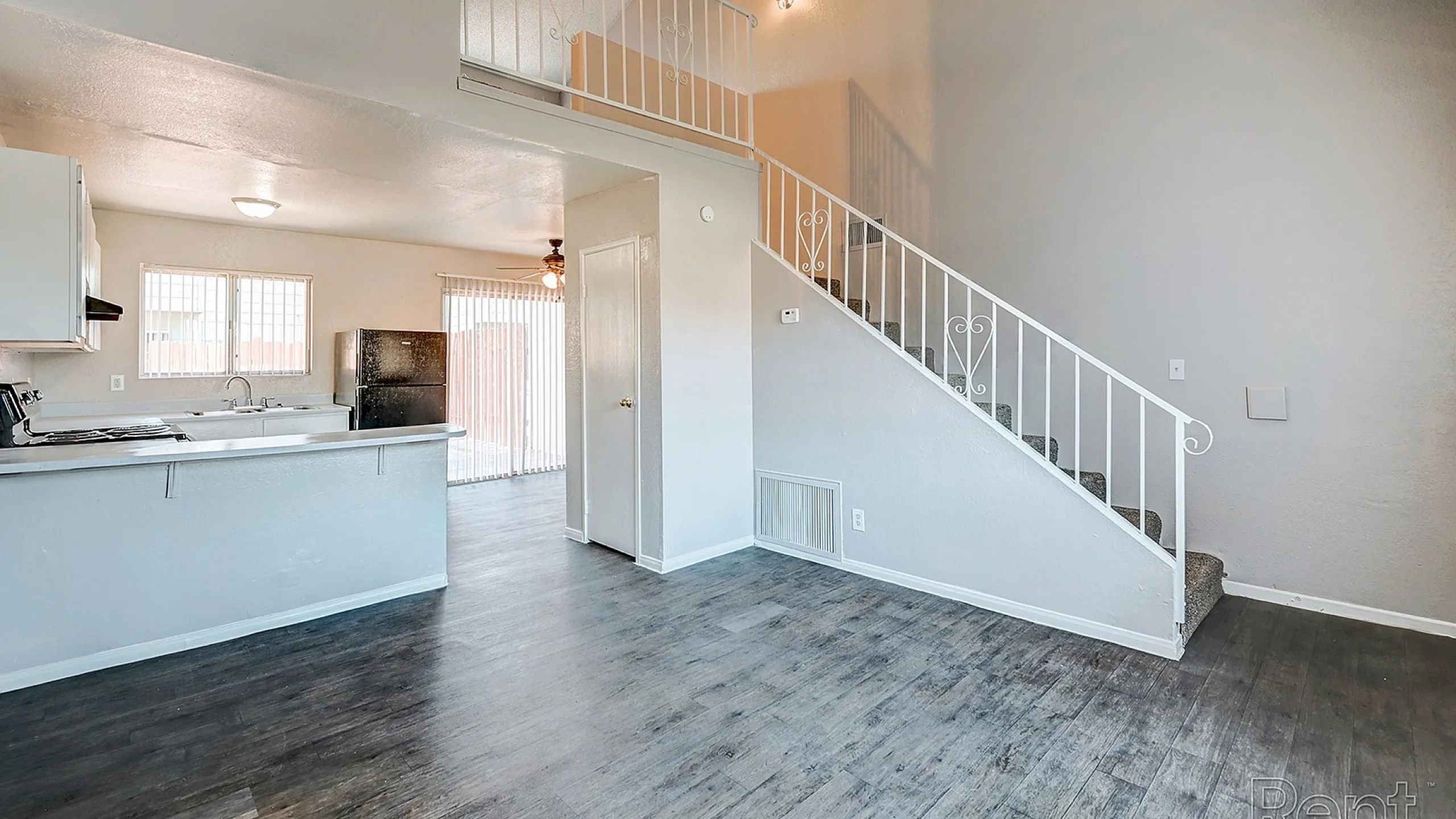 Chic open-concept apartment with sleek hardwood floors, a modern kitchen, and stylish staircase.