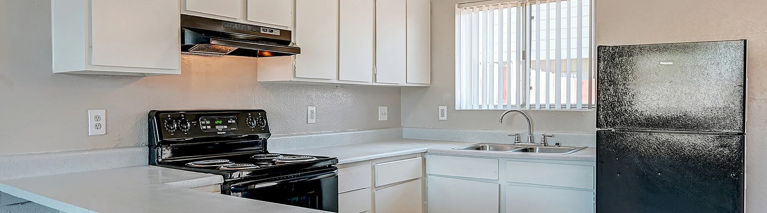 Bright and modern kitchen with white cabinetry, sleek countertops, and a large window for natural light.