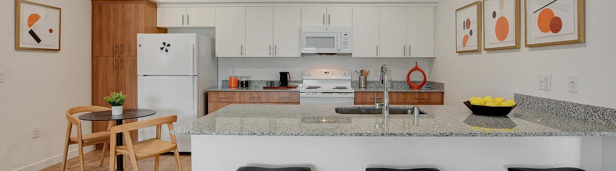 Modern kitchen with sleek countertops, bar stools, and contemporary artwork.