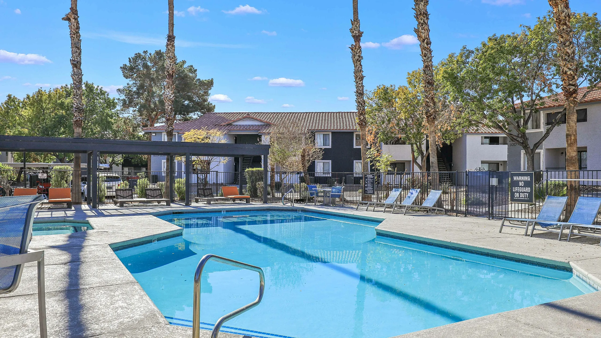 Inviting outdoor pool area surrounded by modern apartment buildings and lush greenery.