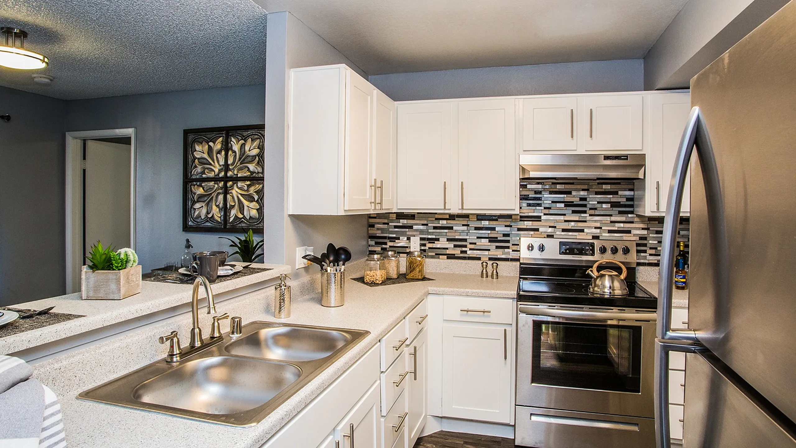 Modern kitchen with sleek stainless steel appliances, stylish backsplash, and elegant lighting.