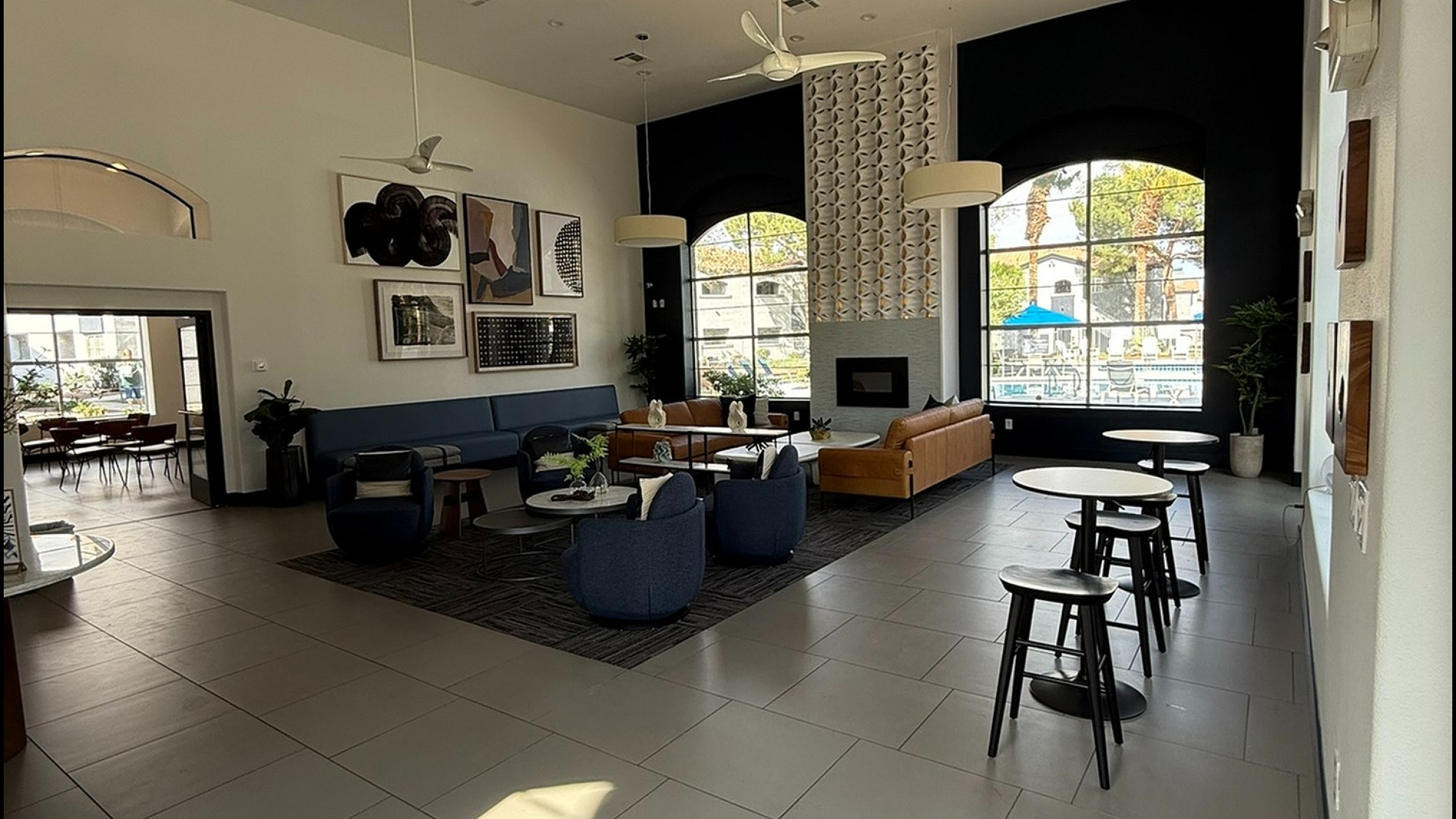 Elegant community lounge with modern seating, high ceilings, and large windows, offering abundant natural light and chic decor.