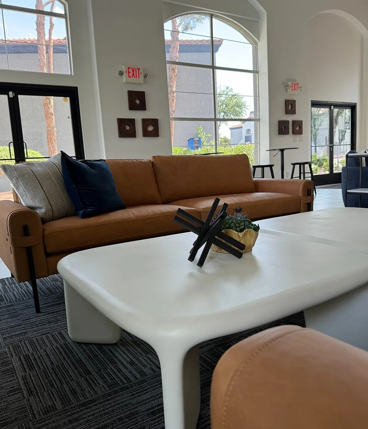 Modern apartment lounge with elegant leather sofa, stylish coffee table, and large windows offering ample natural light.
