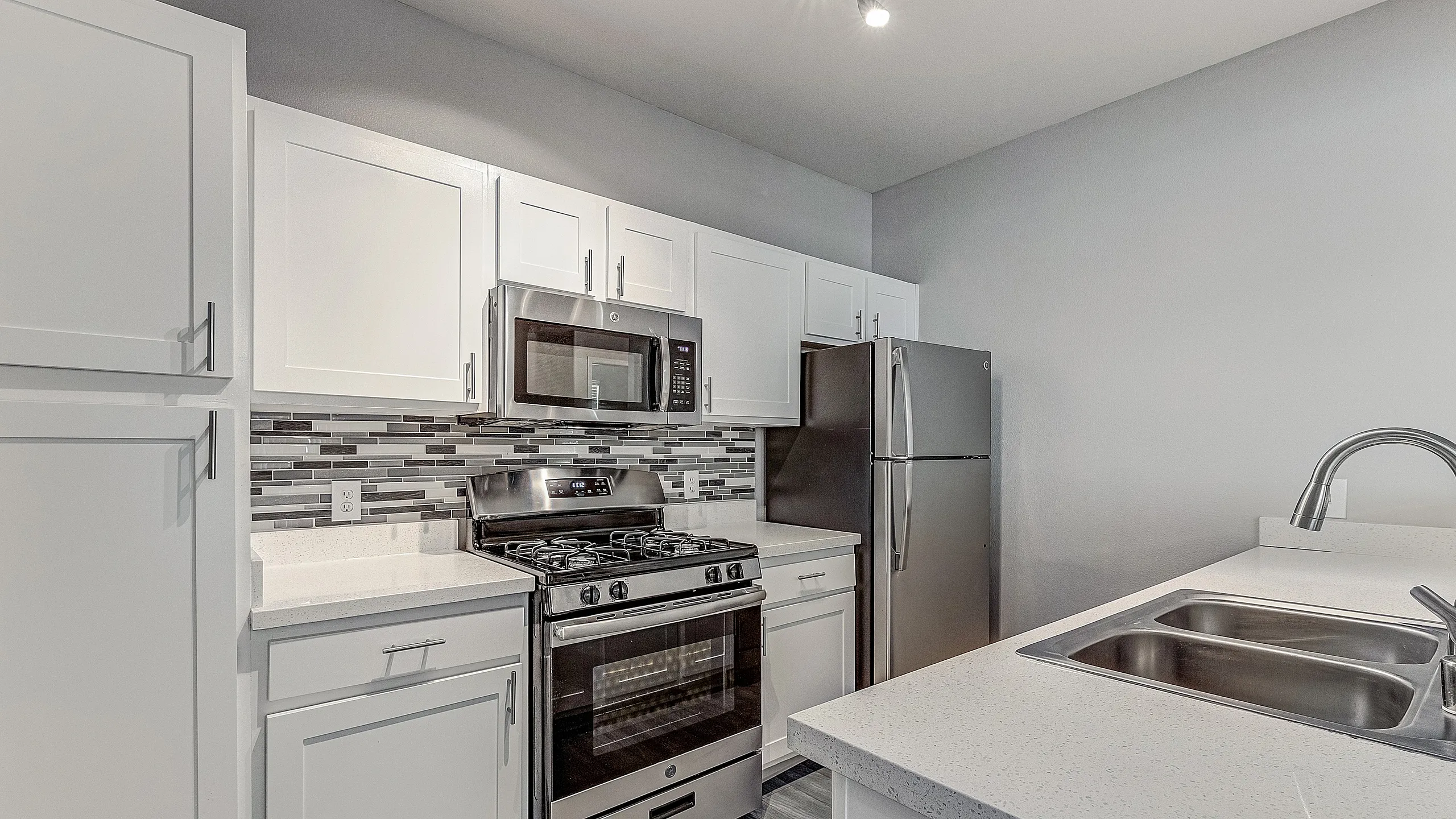 Modern kitchen with sleek white cabinets, stainless steel appliances, and a stylish backsplash.