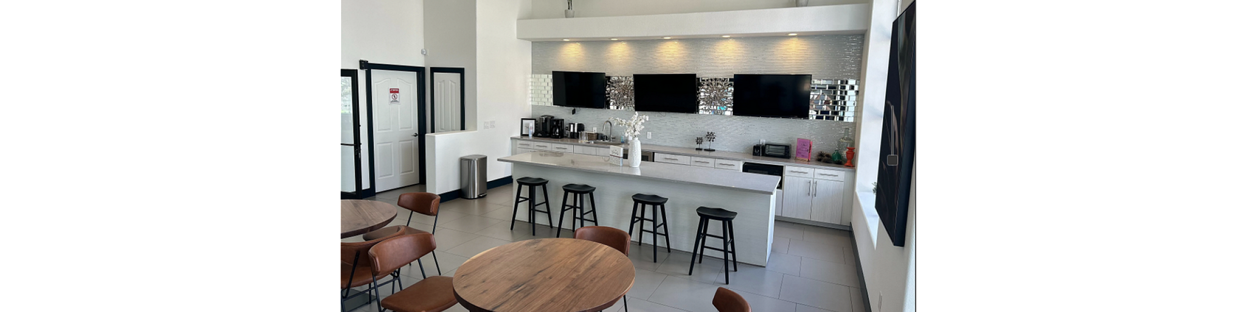 Chic communal kitchen with modern bar seating, elegant decor, and stylish artwork, ideal for gatherings.