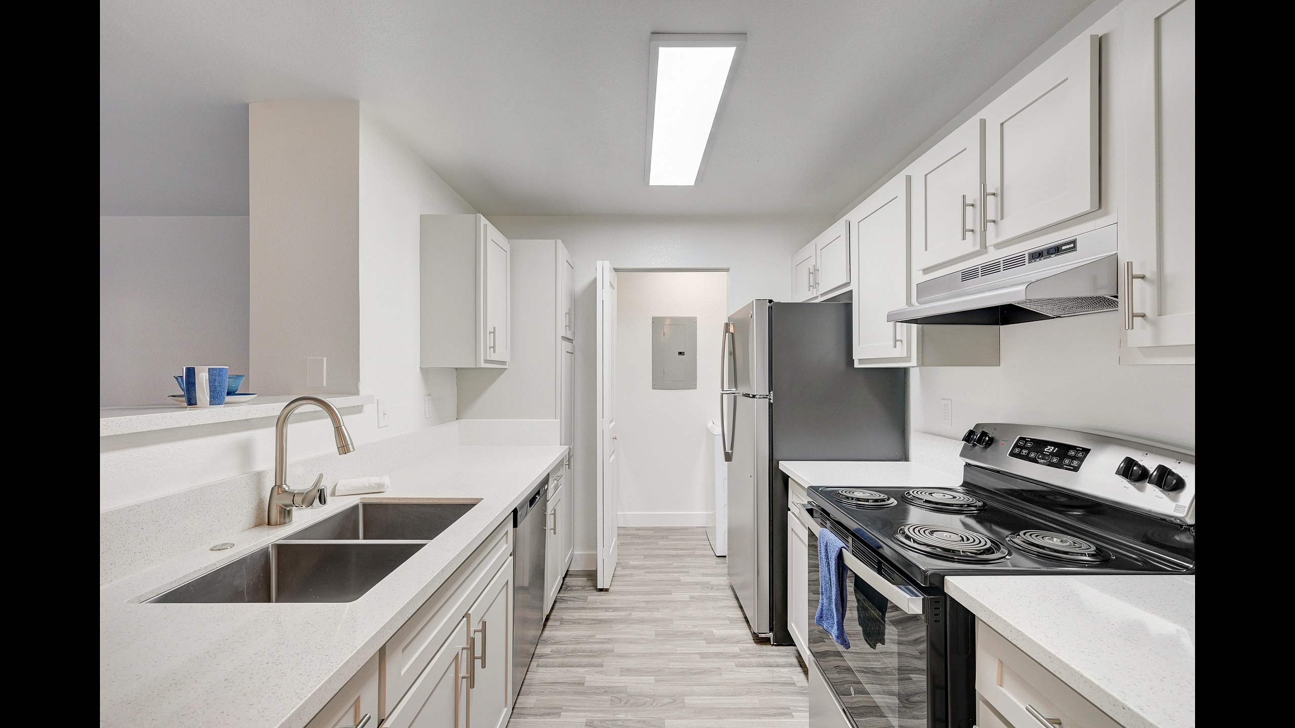 Modern kitchen with sleek white cabinetry, stainless steel appliances, and elegant light wood flooring, offering style and functionality.