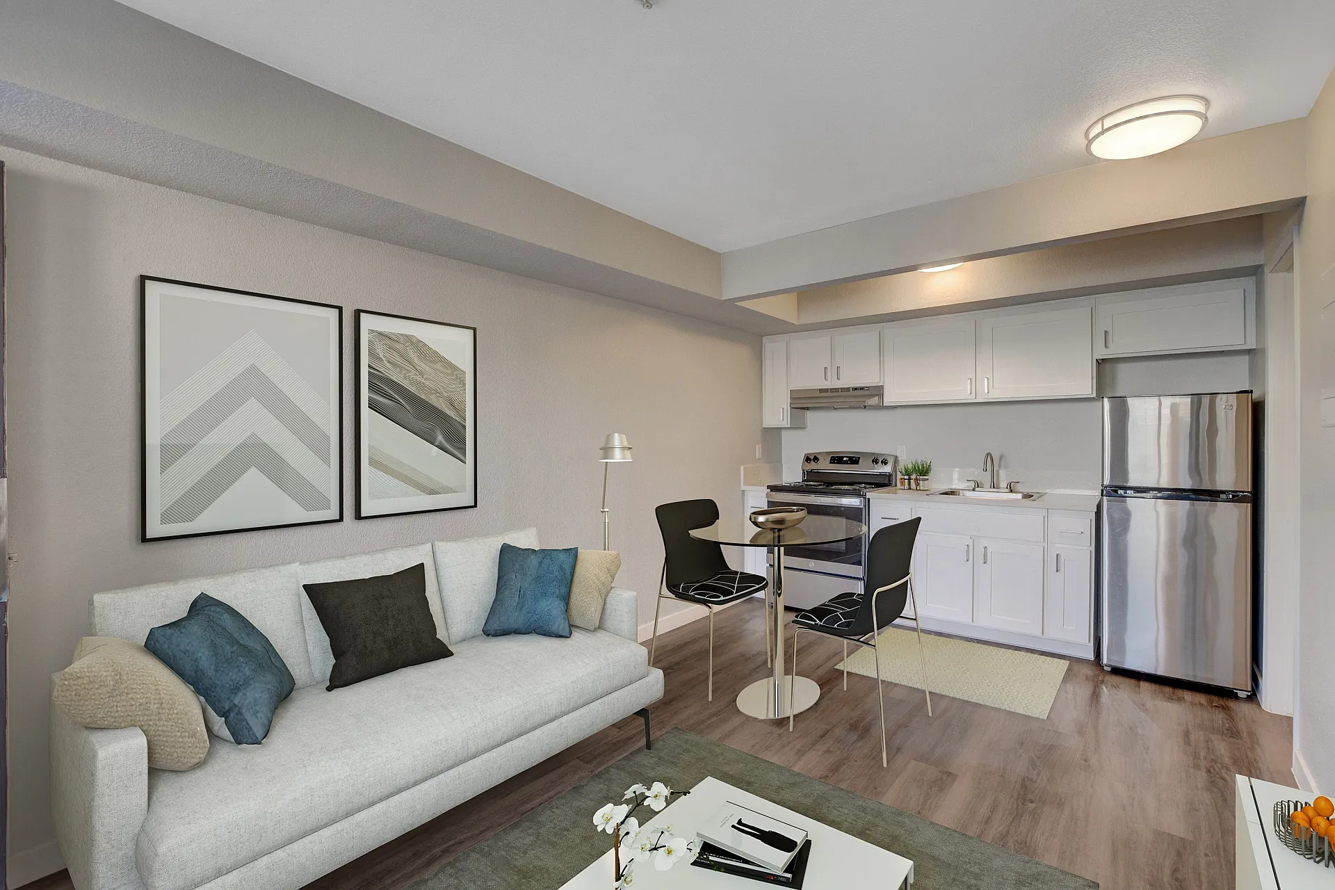 Charming open-concept living room and kitchen with modern decor, featuring a sleek gray sofa, chic dining area, and stylish stainless steel appliances.