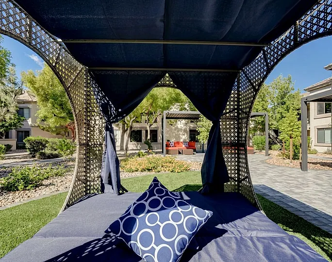 Luxurious outdoor lounge with stylish canopy bed and vibrant gardens, perfect for relaxation and entertaining.
