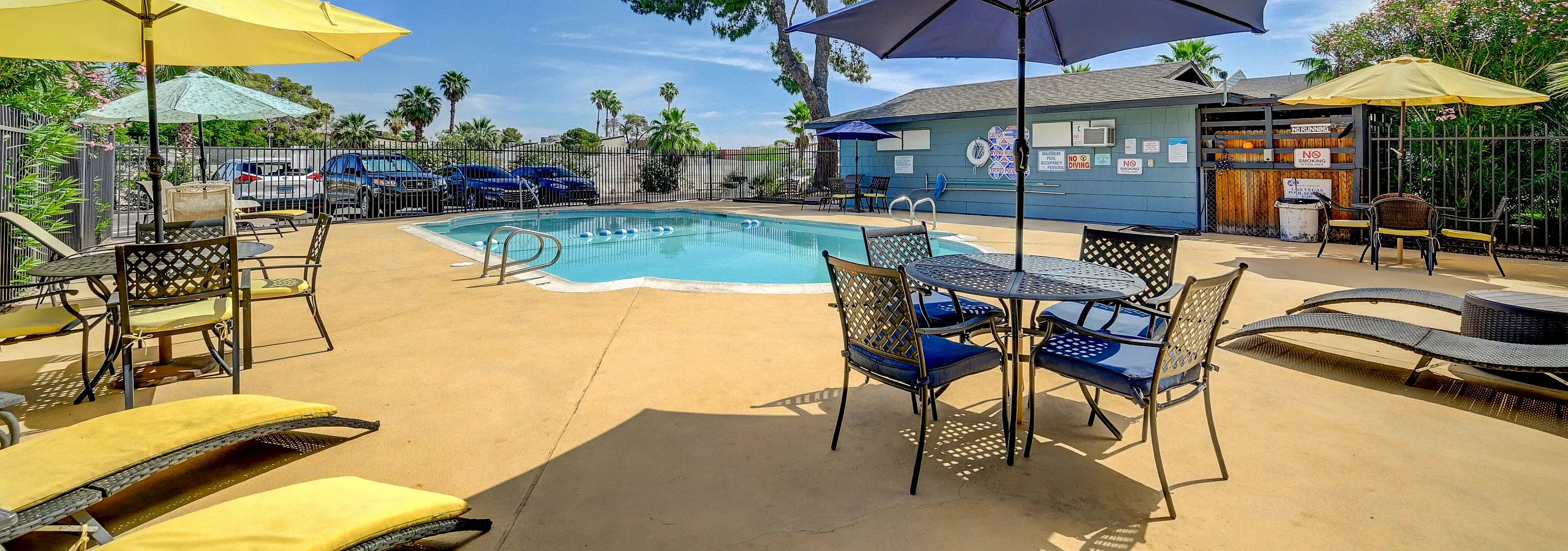 Inviting pool area with colorful umbrellas, stylish lounge chairs, and lush greenery creating a relaxing outdoor oasis.