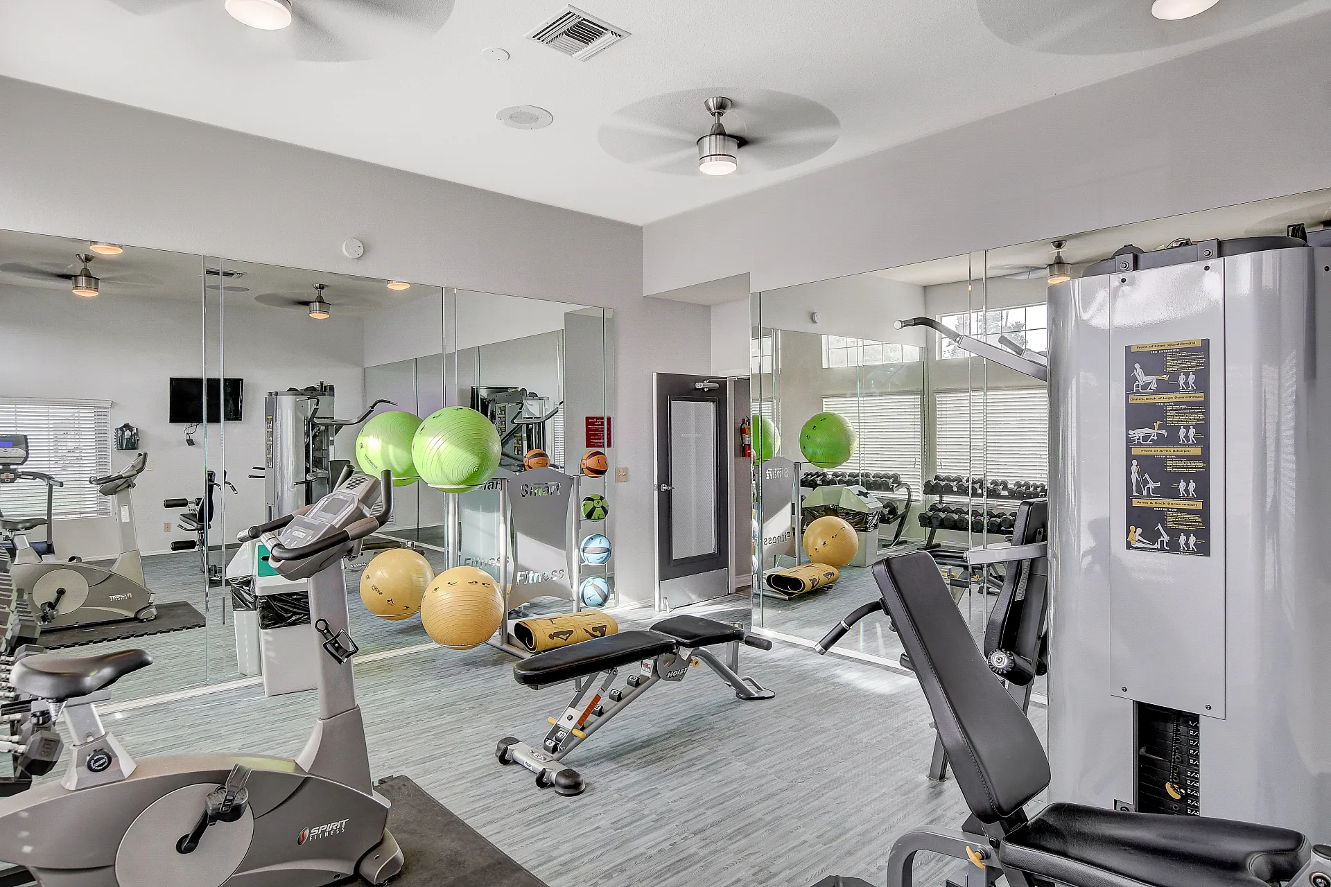 Modern fitness center with state-of-the-art equipment, exercise balls, and mirrored walls for a sleek, gym-ready environment.
