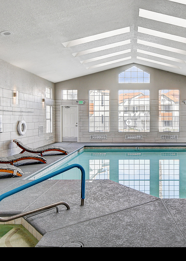 Elegant indoor swimming pool area with skylights, modern lounge chairs, and a luxurious spa corner.