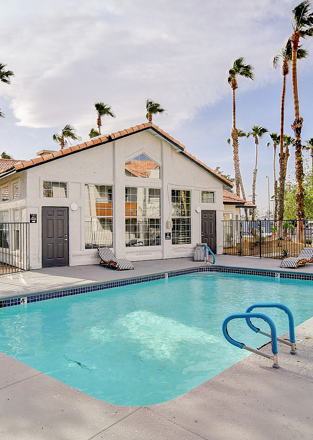 Inviting apartment complex with a sparkling pool, surrounded by palm trees and sun loungers, offering a perfect retreat.