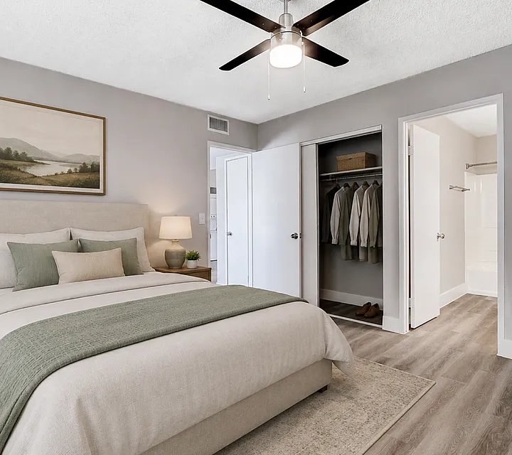 Elegant bedroom showcasing a cozy bed with plush linens, a stylish ceiling fan, and a spacious walk-in closet.