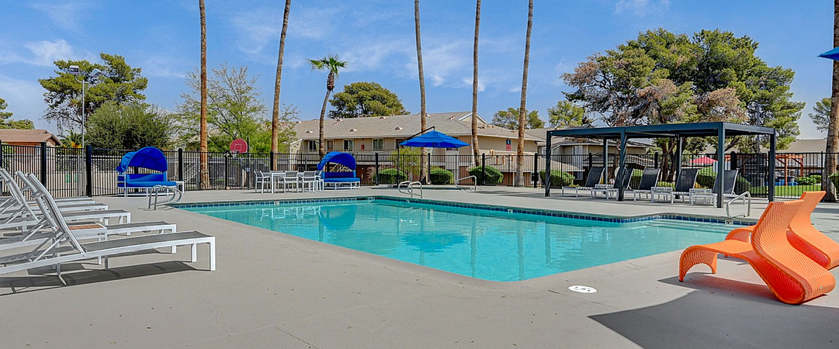 Inviting outdoor pool area with modern lounge chairs and tall palm trees, perfect for relaxation and leisure.