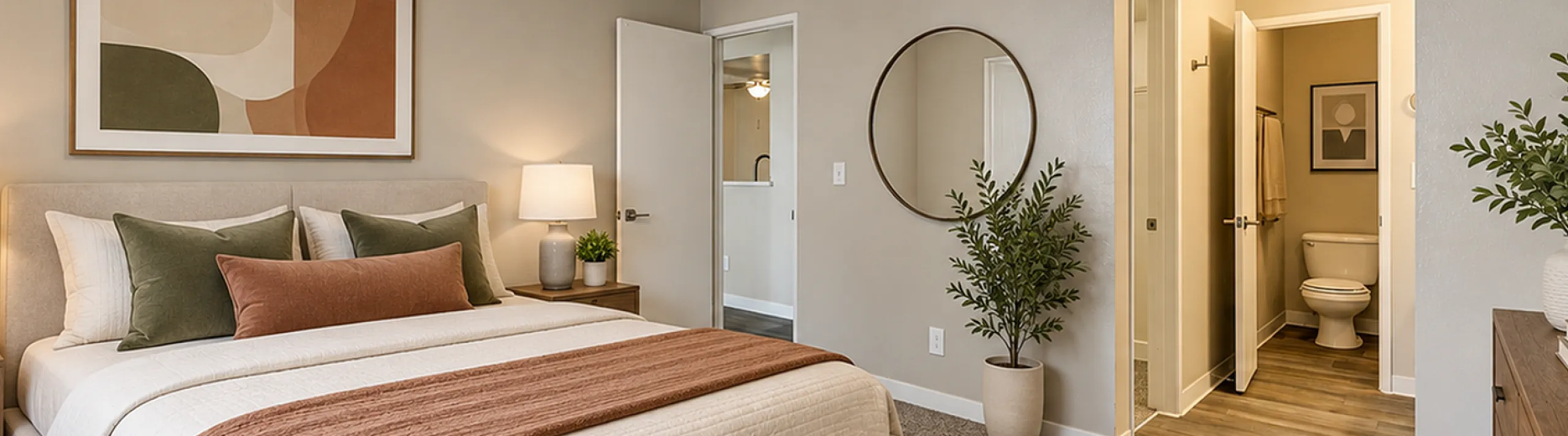 Inviting bedroom showcasing a cozy bed with stylish decor, soft lighting, and modern artwork, leading to a connected en-suite bathroom.