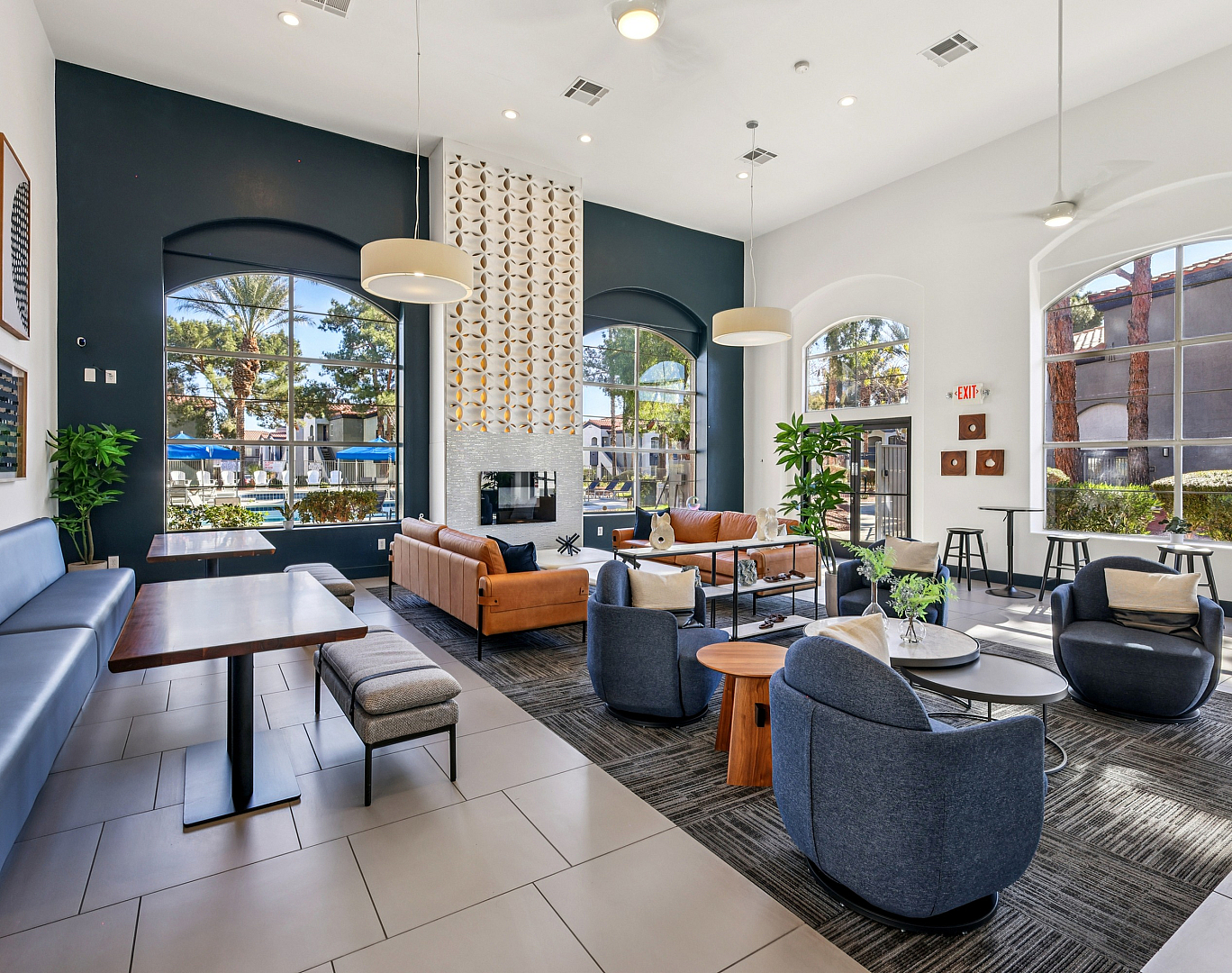Inviting and modern lounge area with stylish sofas, sleek tables, and large windows offering a sunny view of palm trees.