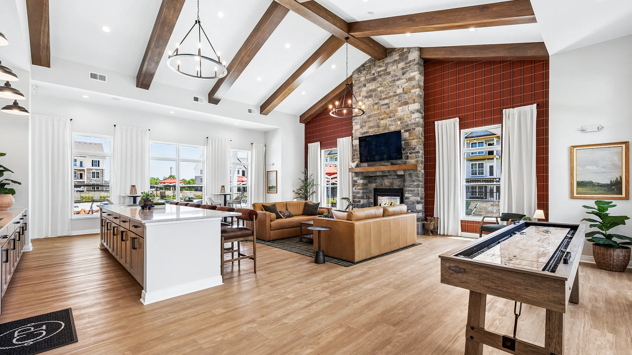 Luxurious open-concept living space with vaulted ceilings, modern kitchen island, cozy seating area, and stone fireplace, perfect for entertaining.