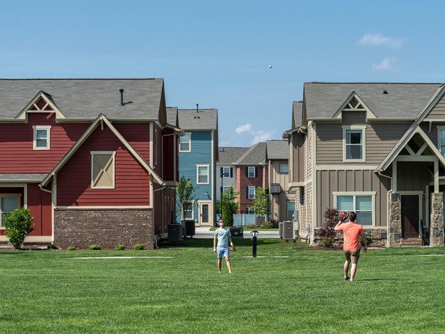 two residents playing catch in the plentiful green space on community grounds