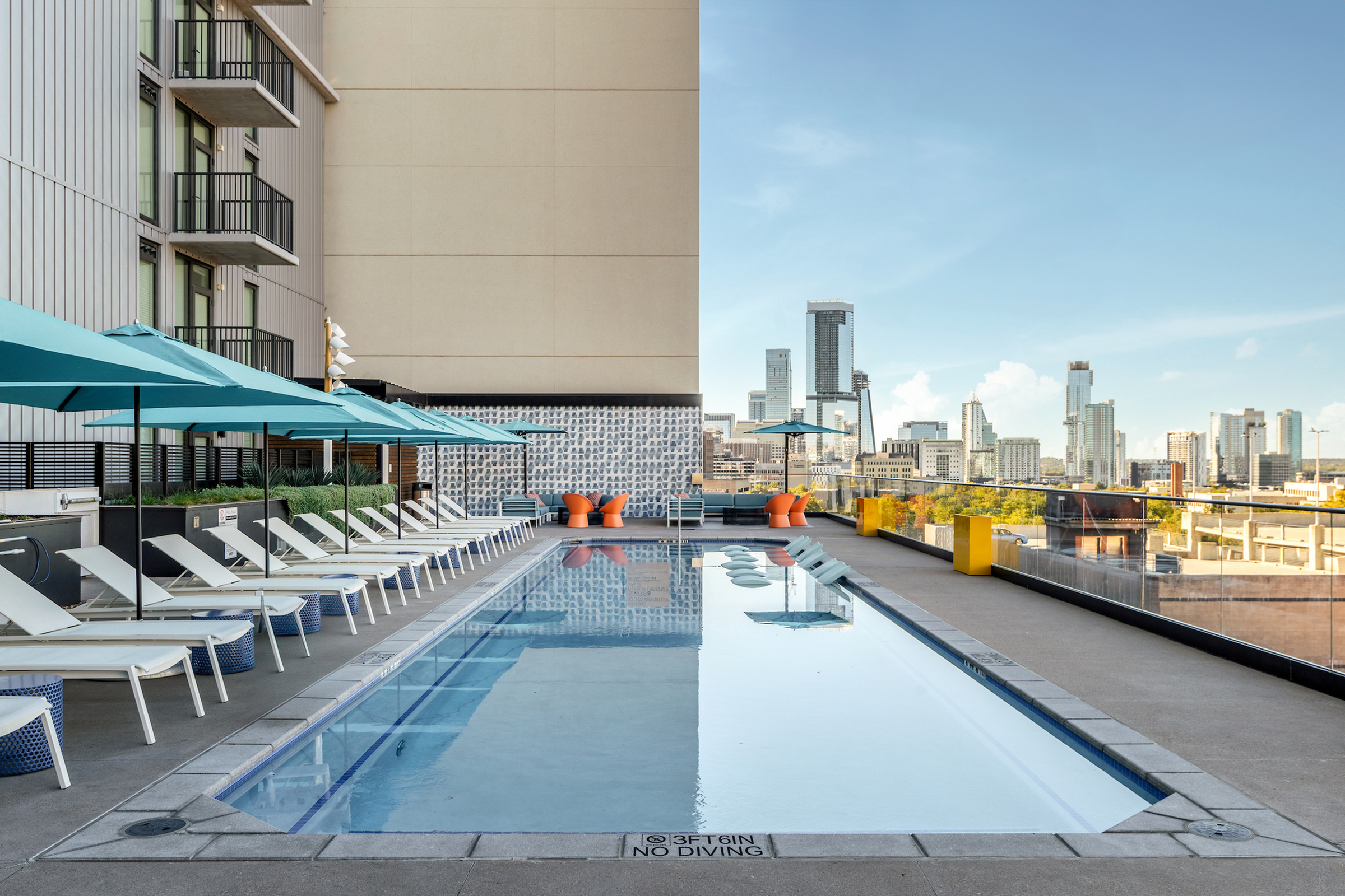 Sparkling pool with sun loungers lining the pool deck looking out at the city of Austin