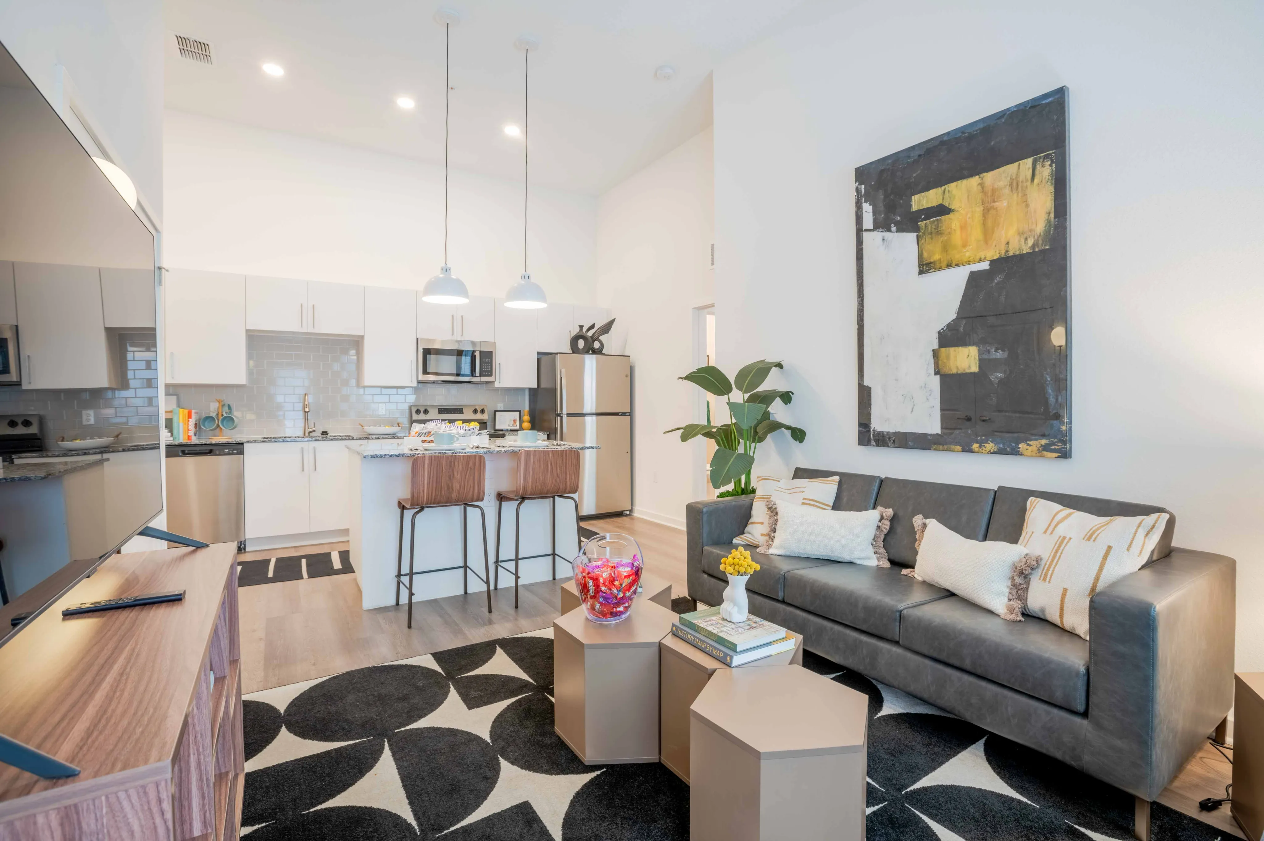Model apartment living room with white walls and hardwood floors looking into the kitchen