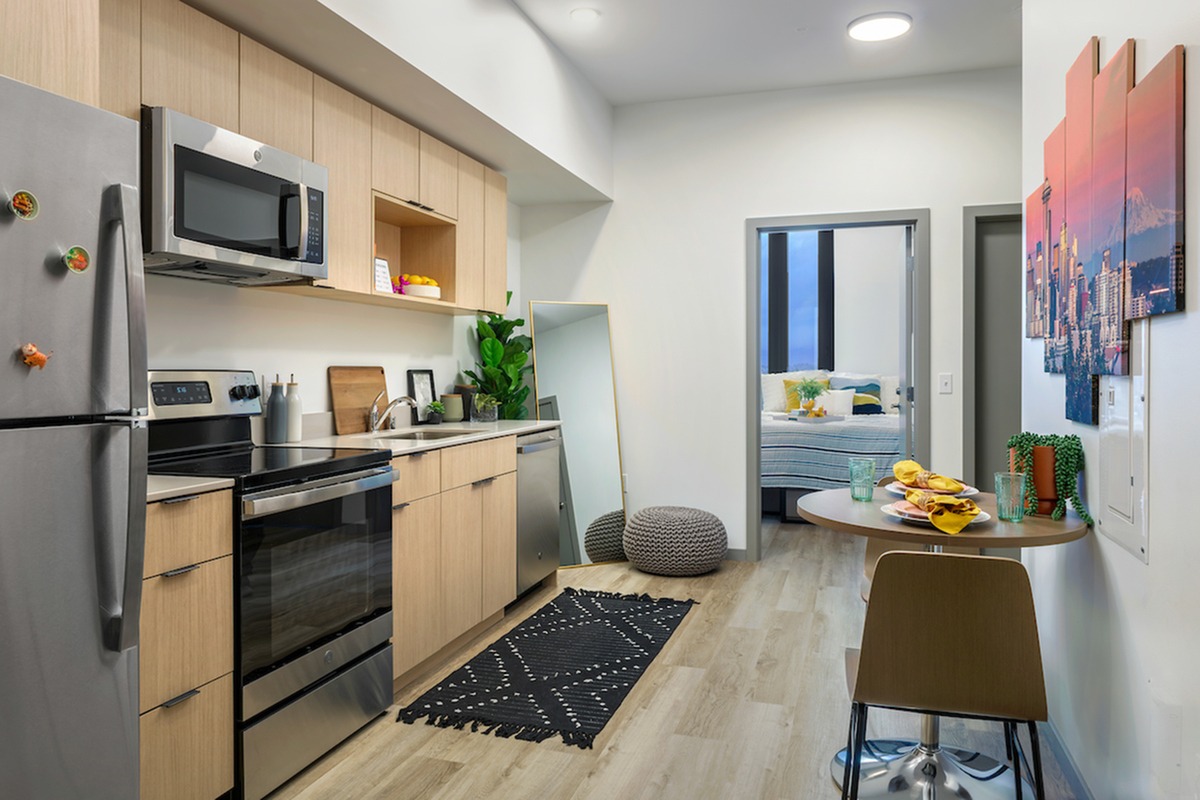 Model kitchen at our apartments in Seattle, featuring wood grain floor paneling and stainless steel appliances.