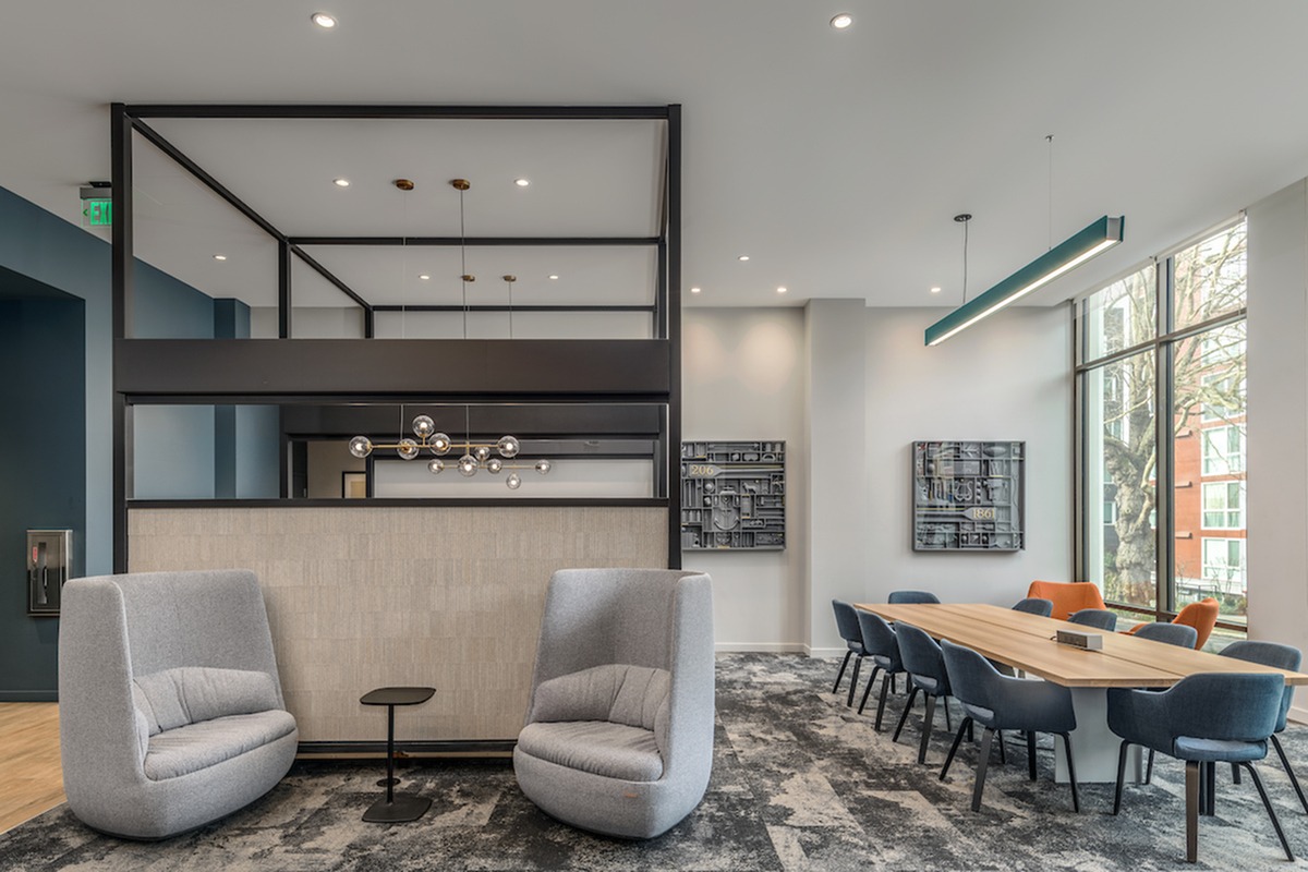 Common lounge at our apartments in Seattle, featuring carpeted floors, cushioned chairs, and large windows.