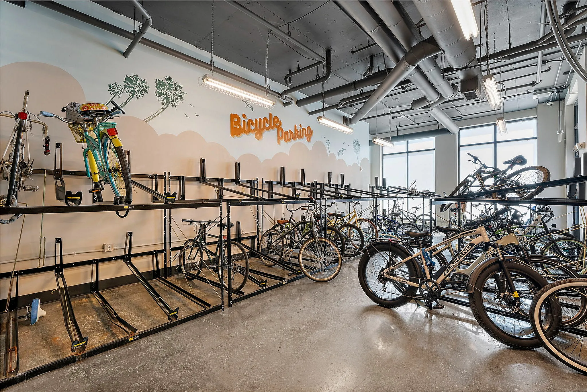 Modern bicycle parking area with sleek bike racks and creative wall art, offering convenient and secure storage for residents.
