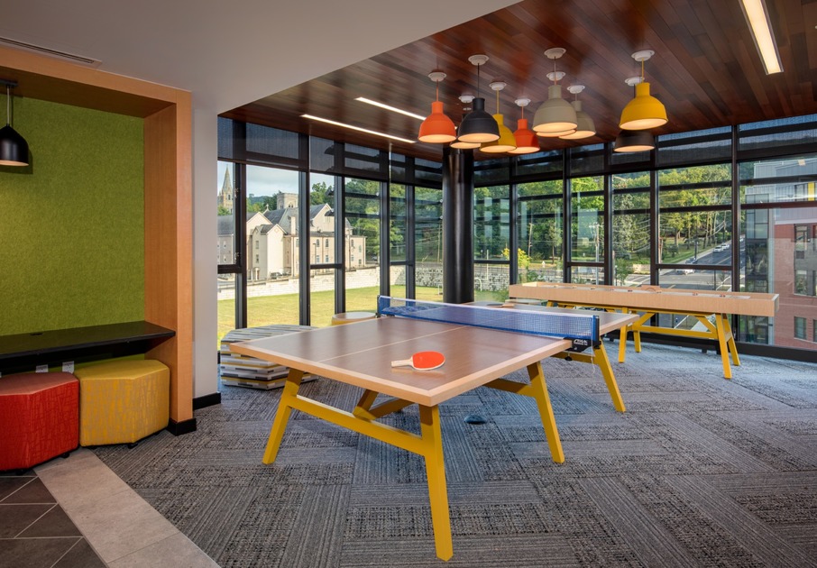Resident lounge at Southside Commons apartments for rent in Bethlehem, PA, featuring carpeted flooring and a ping pong table.