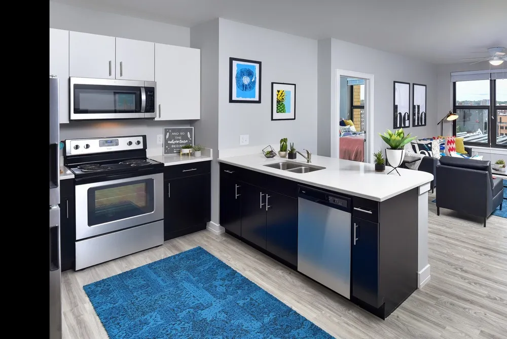 Model kitchen at One On Centre Apartments in Pittsburgh, featuring wood grain floor paneling and stainless steel appliances.