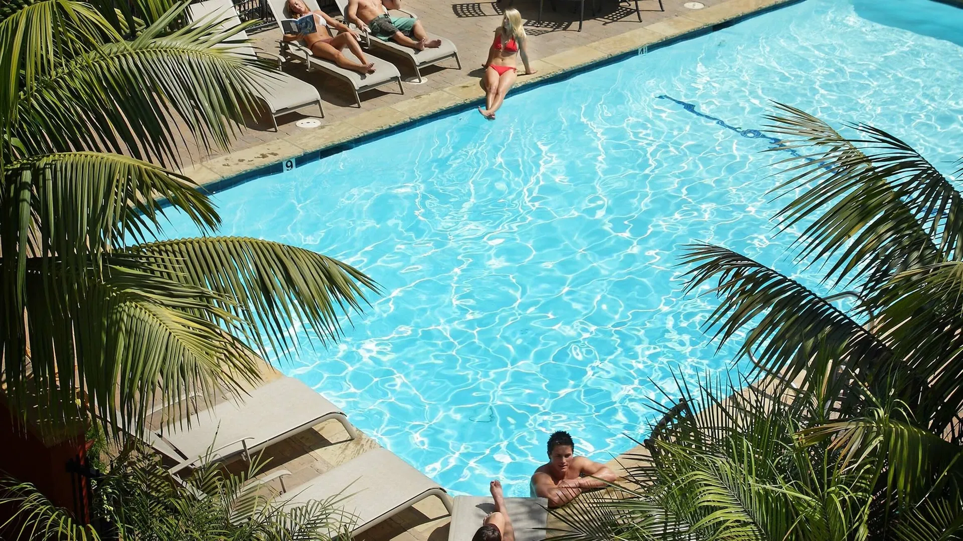 Residents enjoying the sparking pool and sun loungers that line the edge