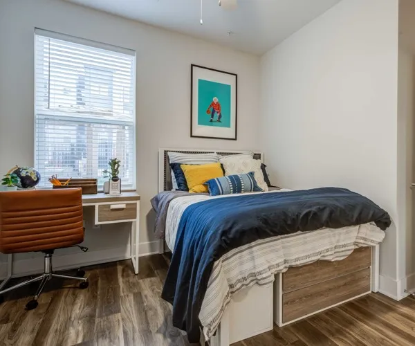 Model bedroom at Union Blacksburg apartments for rent near Virginia Tech, featuring wood grain flooring and a desk.
