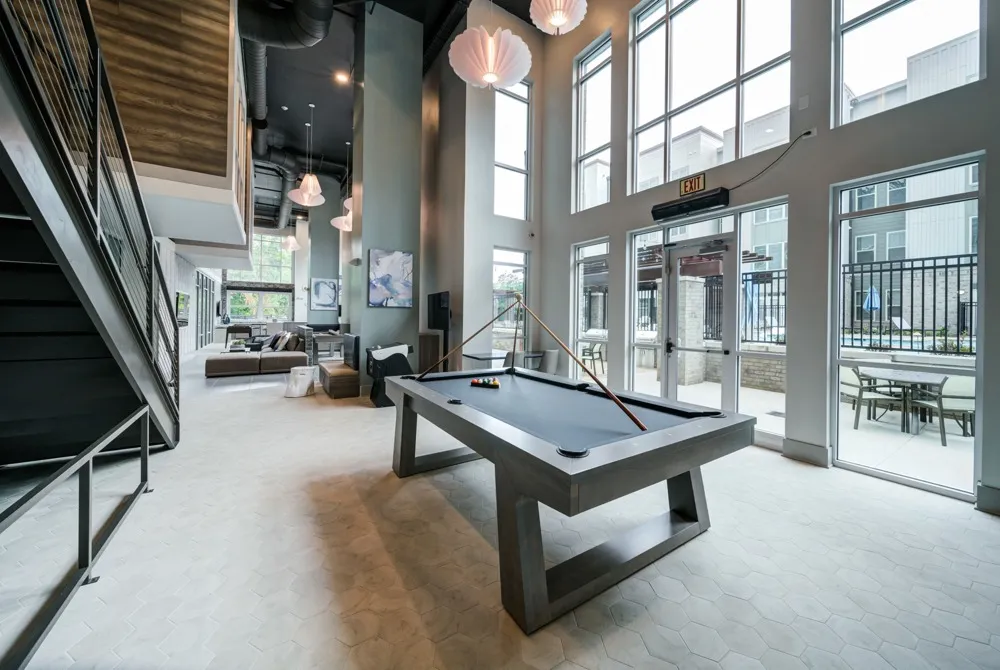 Resident lounge at Union Chapel Hill apartments in Chapel Hill, NC, featuring a game table and floor to ceiling windows.