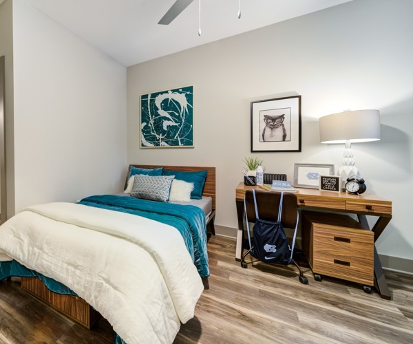 Model bedroom at Union Chapel Hill apartments in Chapel Hill, NC, featuring wood grain flooring and modern interior decorating.