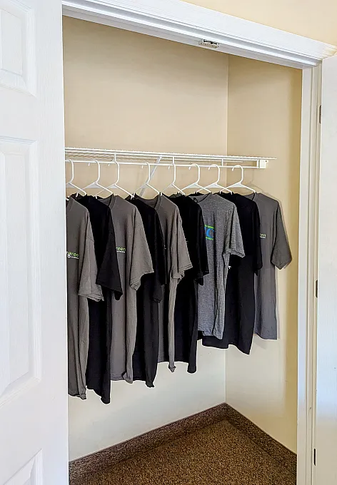 closet with hanging grey and black shirts