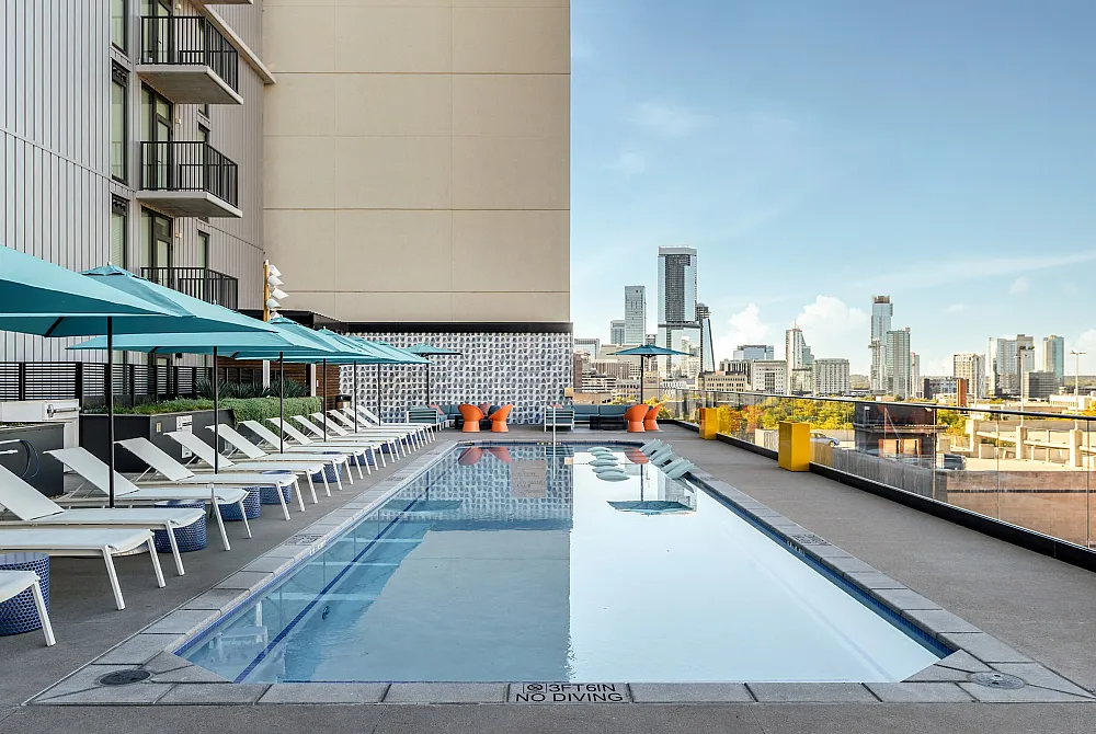 Sparkling pool with sun loungers lining the pool deck looking out at the city of Austin
