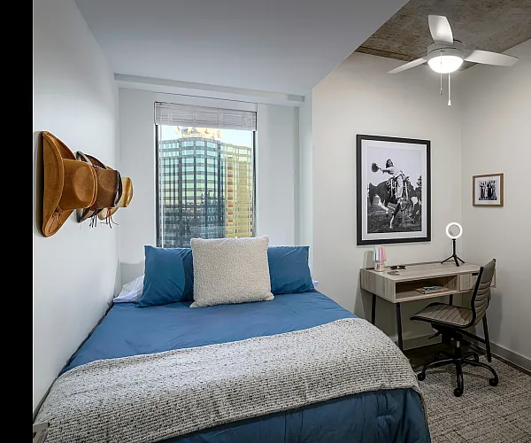 Model apartment bedroom with full size bed, desk, and desk chair